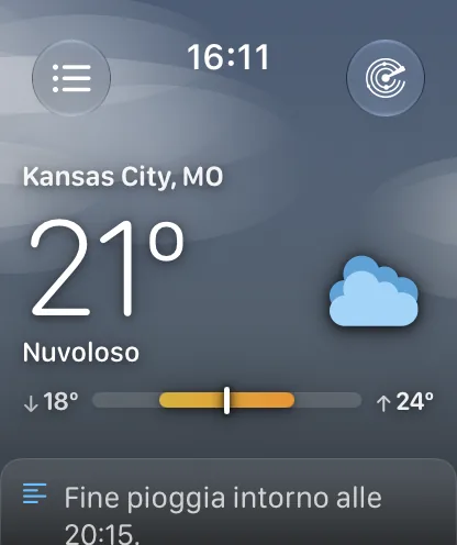 La schermata principale sotto un cielo grigio-azzurro coperto con morbide fasce di foschia, che mostra Kansas City, MO a 64 gradi e Nuvoloso e una barra dell’intervallo con una freccia verso il basso e 62 gradi a sinistra e una freccia verso l’alto e 71 gradi a destra.