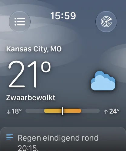 Het hoofdscherm onder een bewolkte grijsblauwe lucht met zachte nevelbanden, met Kansas City, MO op 64 graden en Zwaarbewolkt, en een bereikbalk met links een pijl omlaag en 62 graden en rechts een pijl omhoog en 71 graden.